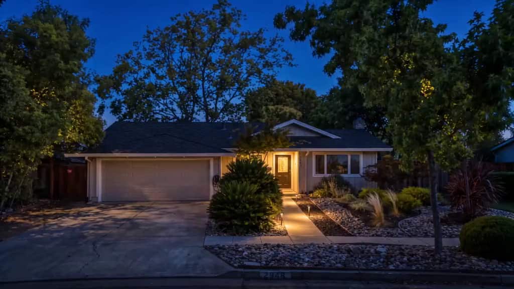 The house at dusk, the entry and walk lit warm under a deep blue sky.